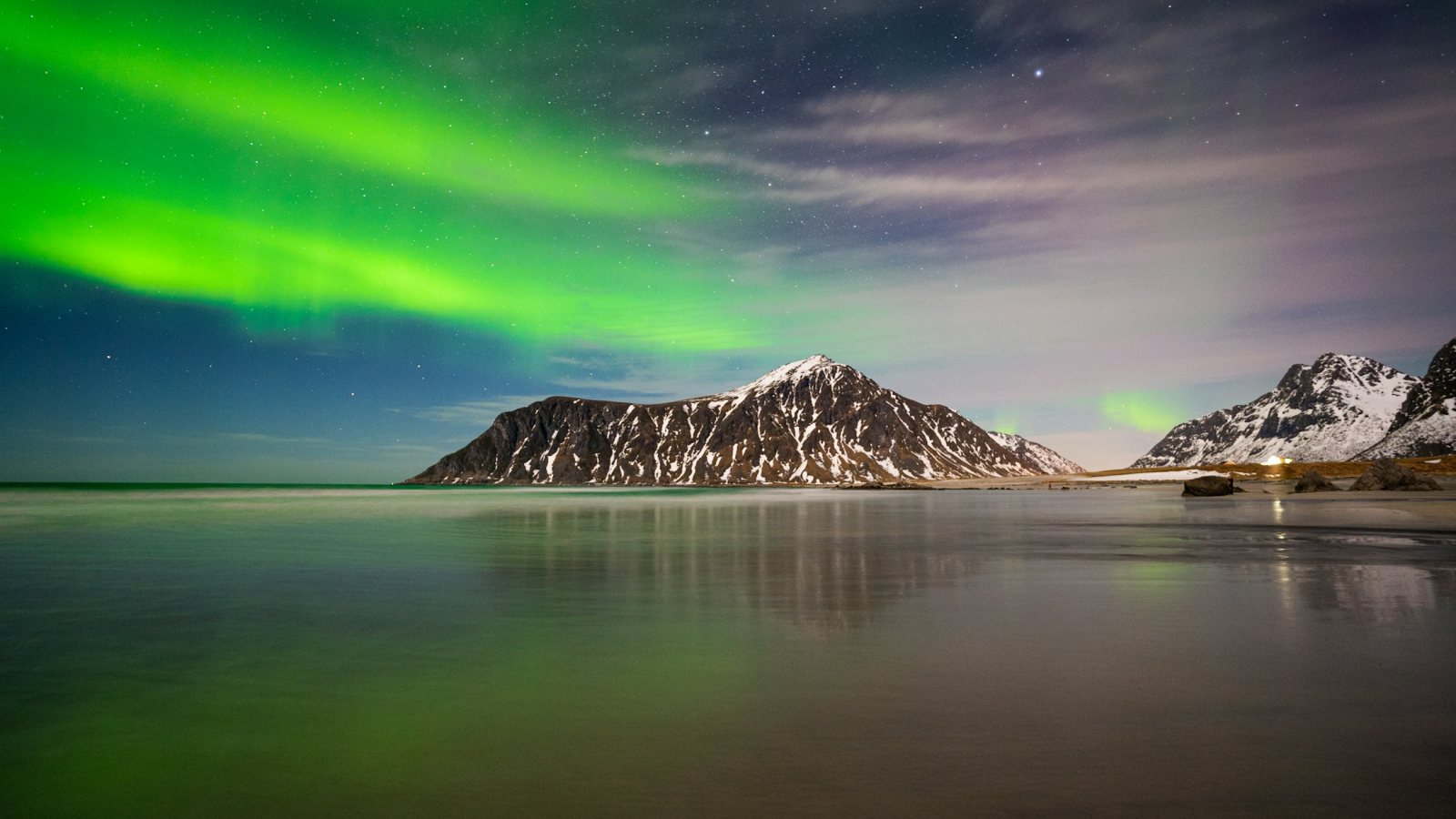 Grüne Nordlichter über verschneiten Bergen auf den Lofoten